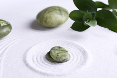 Photo of Zen concept. Stones, leaves and pattern on white sand