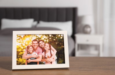Photo of Frame with family photo on wooden table in bedroom, space for text