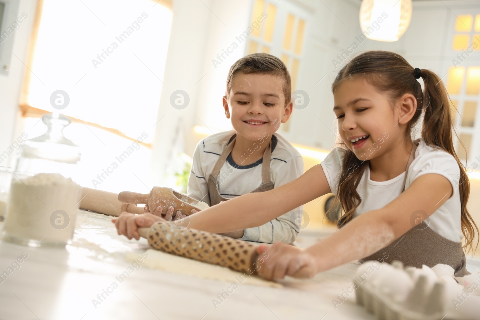 Photo of Cute little children cooking dough together in kitchen