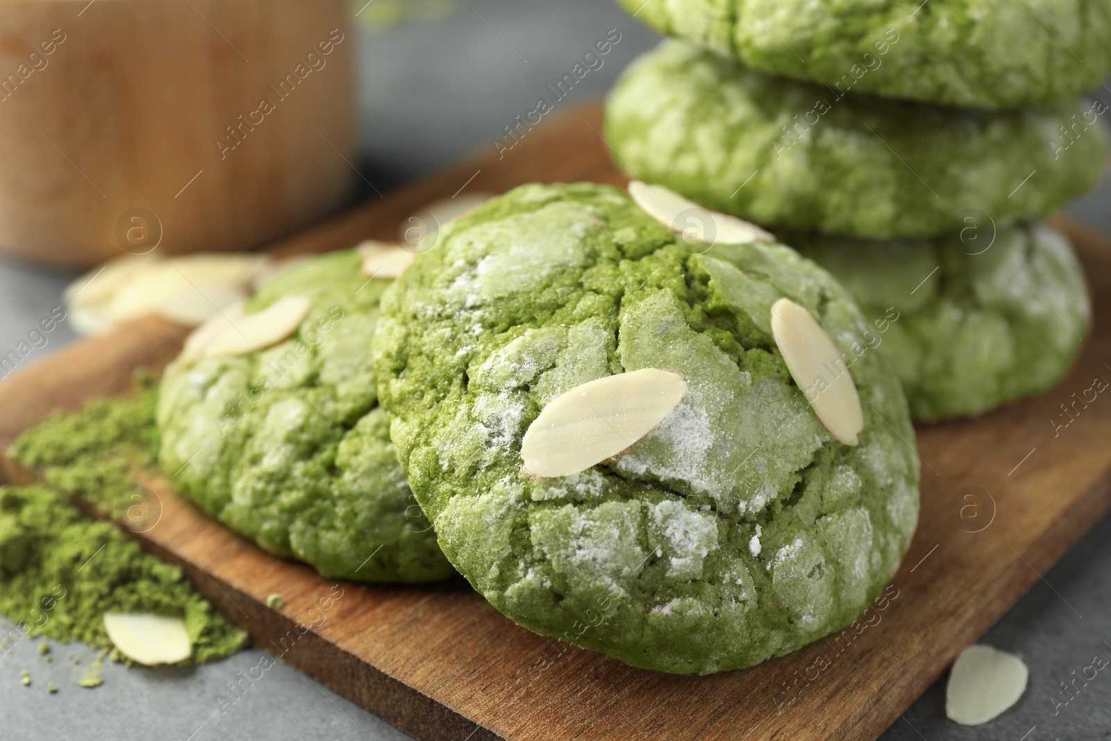 Photo of Tasty matcha cookies, almond flakes and powder on grey table, closeup