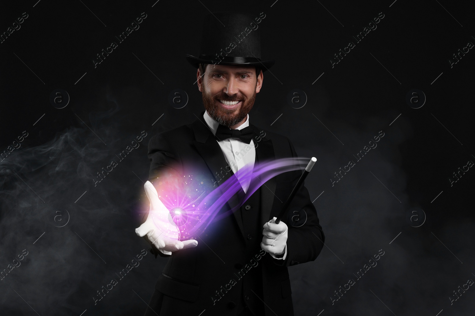 Image of Magic and sorcery. Magician with wand and fantastic light in smoke on dark background