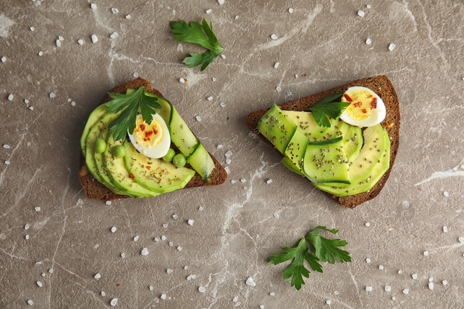 Photo of Tasty crisp rye toasts with avocado and quail egg on table, flat lay