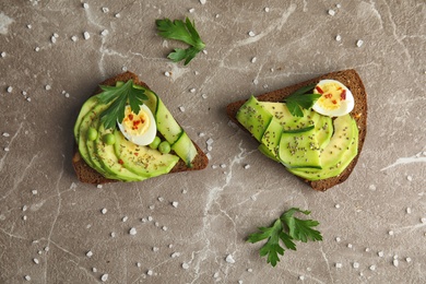 Photo of Tasty crisp rye toasts with avocado and quail egg on table, flat lay