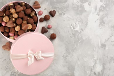 Photo of Different delicious chocolate candies in box on grey marble table, flat lay. Space for text