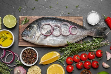 Flat lay composition with fresh raw dorado fish and ingredients on black table