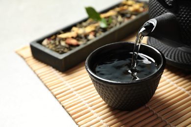 Photo of Pouring green tea into cup on table. Space for text
