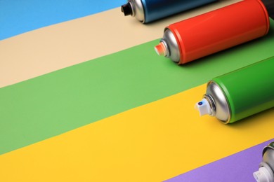 Photo of Cans of different spray paints on color background, space for text. Graffiti supplies