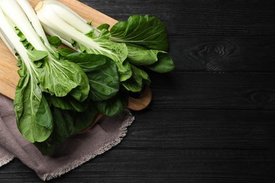 Photo of Fresh green pak choy cabbages on black wooden table, top view. Space for text