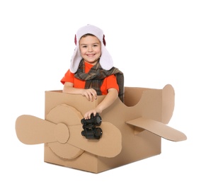 Cute little boy playing with binoculars and cardboard airplane on white background