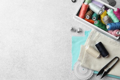 Photo of Flat lay composition with spools of threads and sewing tools on light background, space for text