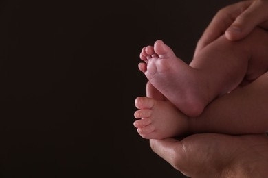 Photo of Father holding his baby against dark background, closeup. Space for text
