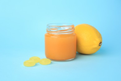 Photo of Cough drops, fresh lemon and honey on light blue background