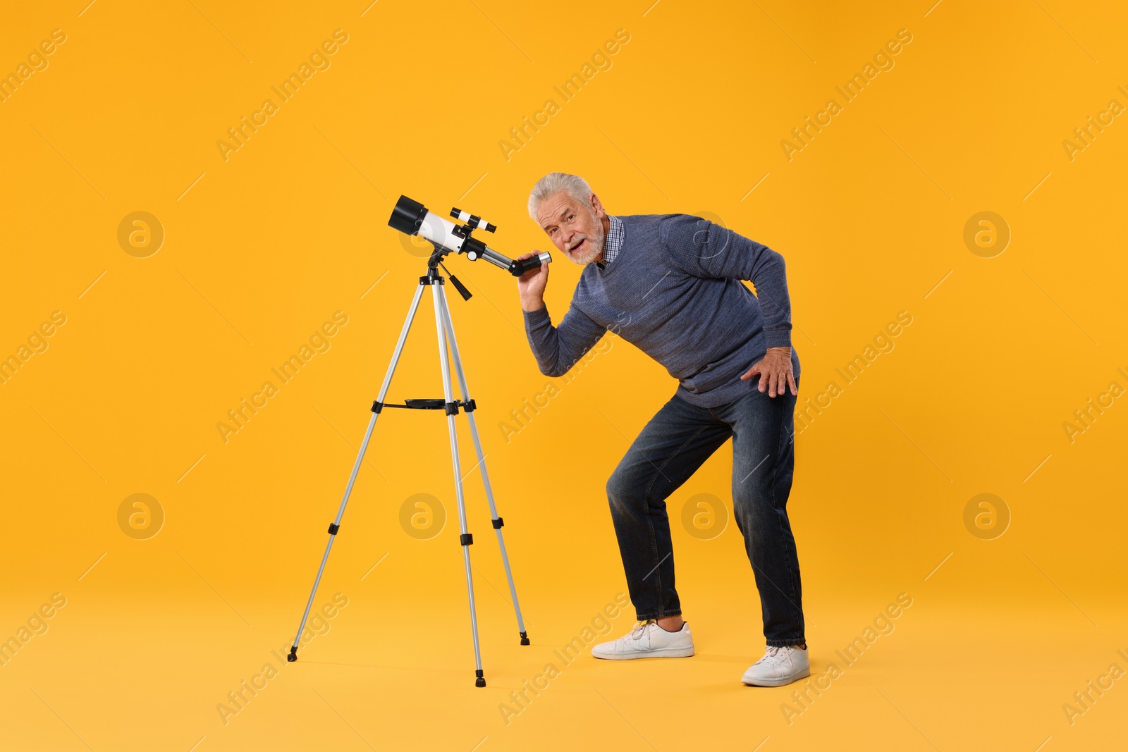 Photo of Senior astronomer with telescope on yellow background