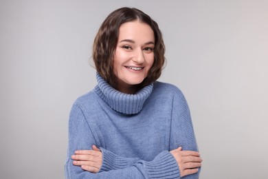 Photo of Smiling woman with dental braces in warm sweater on grey background