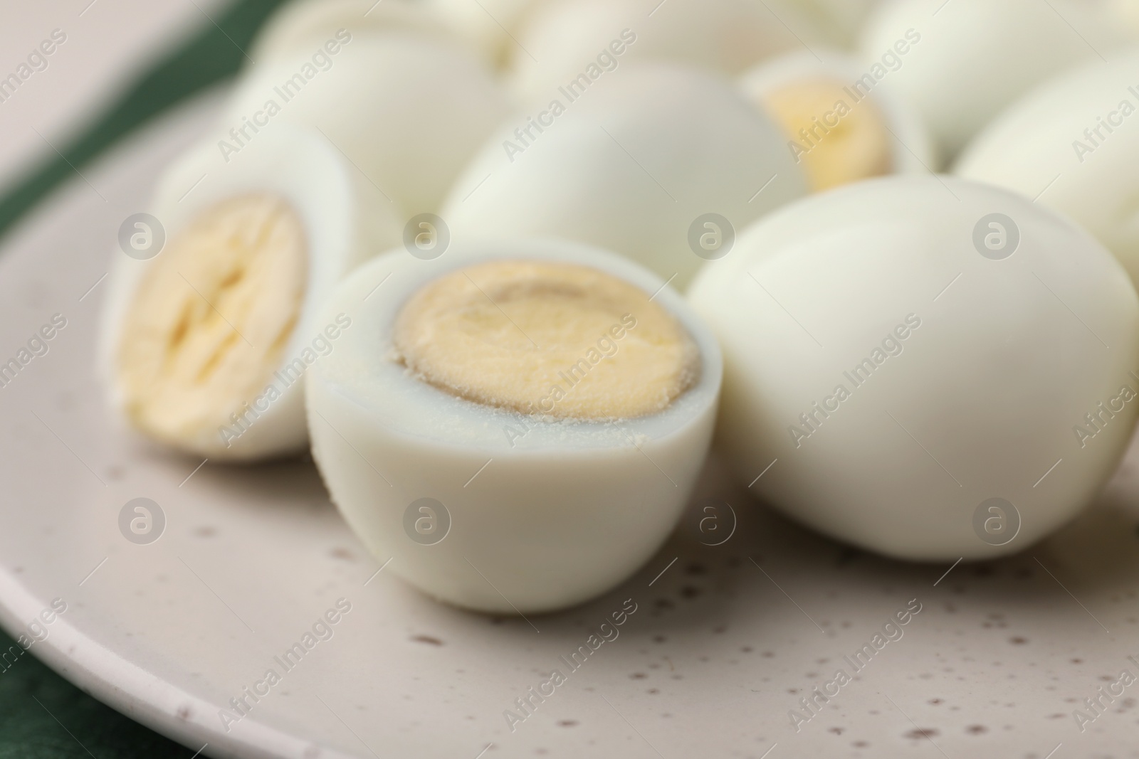 Photo of Many peeled hard boiled quail eggs on plate, closeup