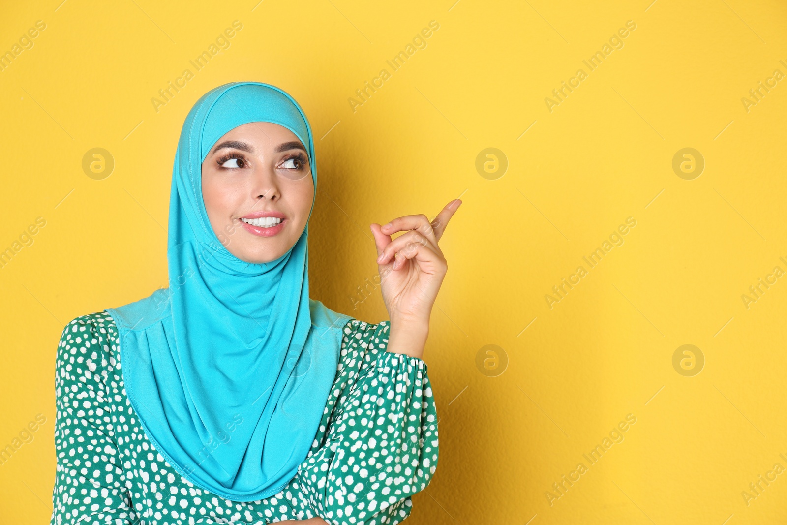 Photo of Portrait of young Muslim woman in hijab against color background. Space for text