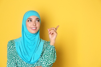 Photo of Portrait of young Muslim woman in hijab against color background. Space for text