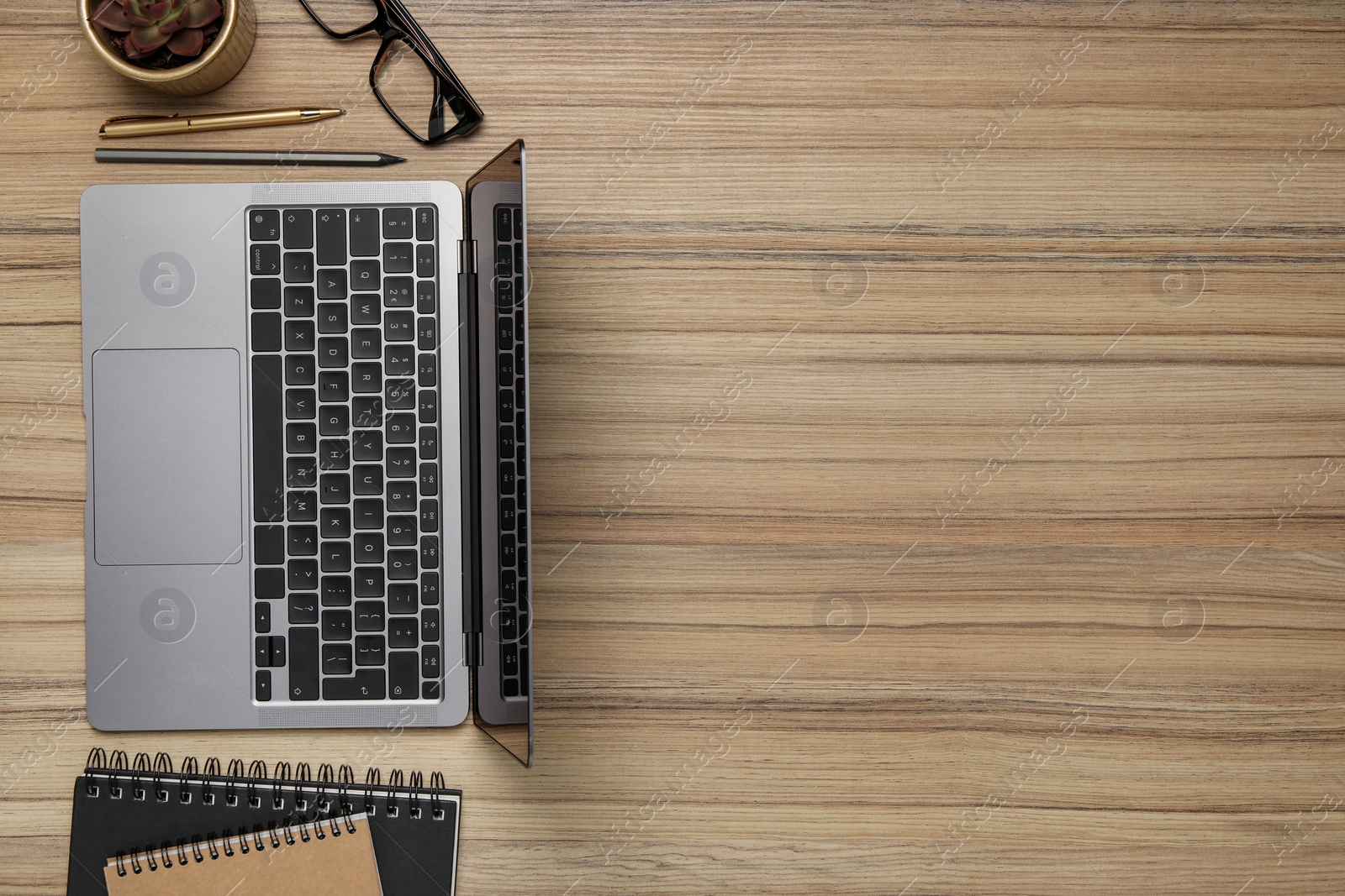 Photo of Modern laptop, notebooks and glasses on wooden table, flat lay. Space for text