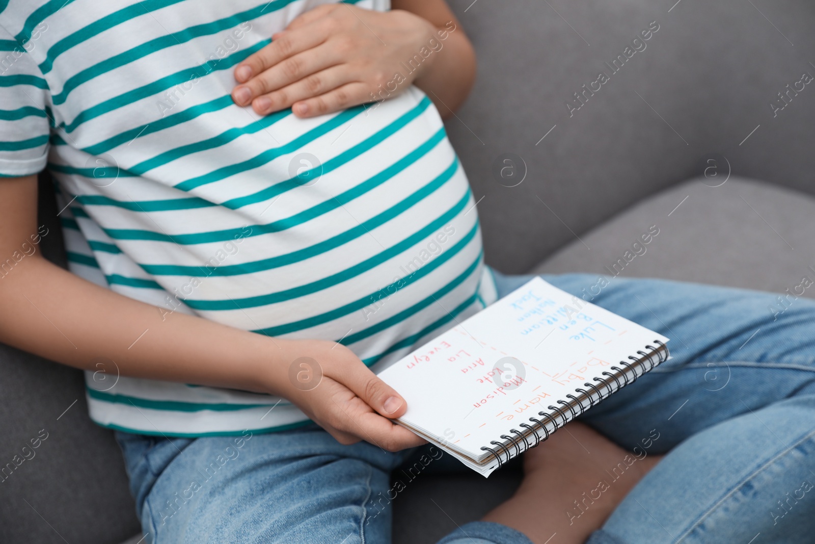 Photo of Pregnant woman with baby names list sitting on sofa, closeup