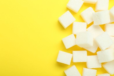 Photo of White sugar cubes on yellow background, top view. Space for text