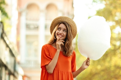 Photo of Happy young woman with cotton candy outdoors