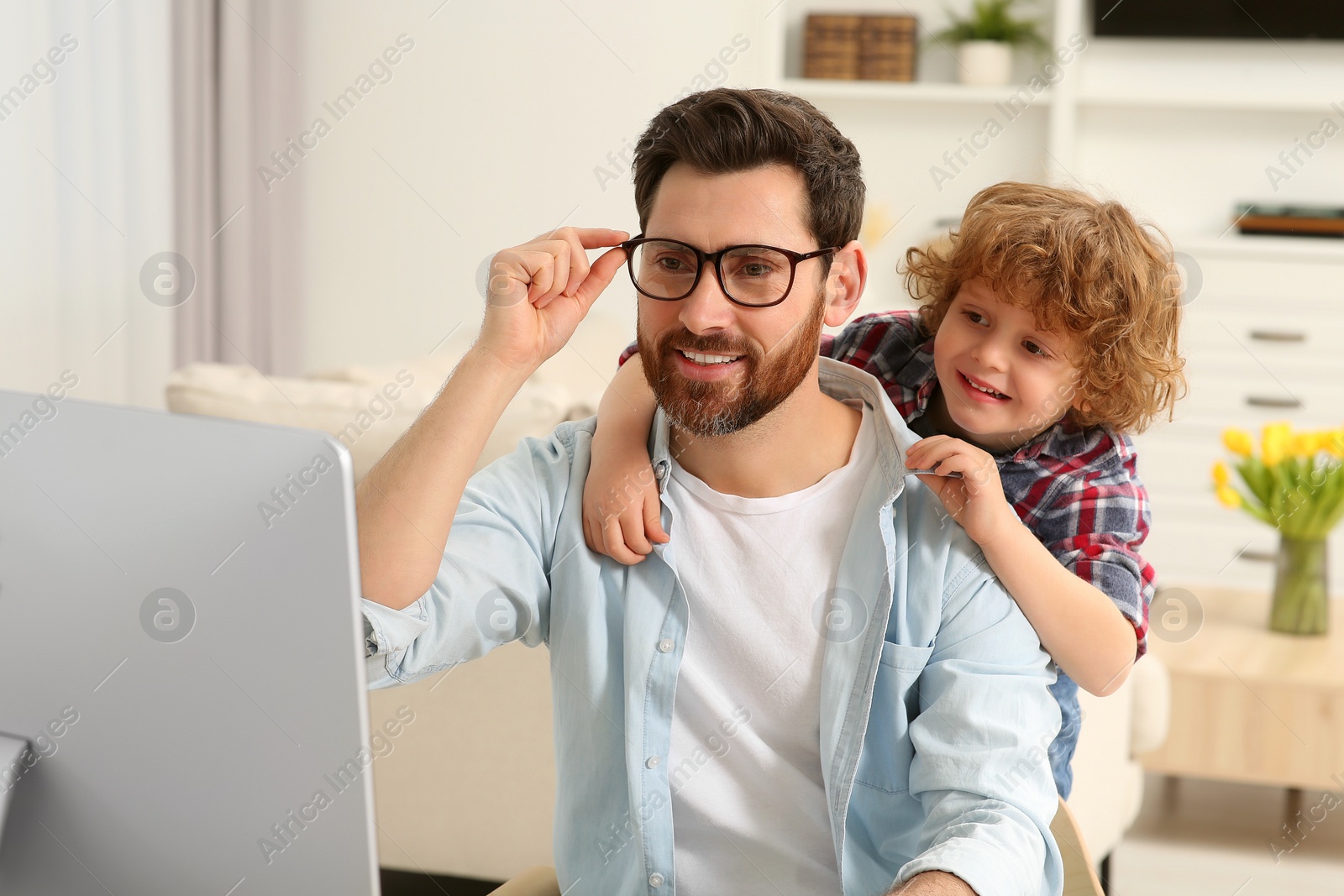 Photo of Man working remotely at home. Father with his child at desk