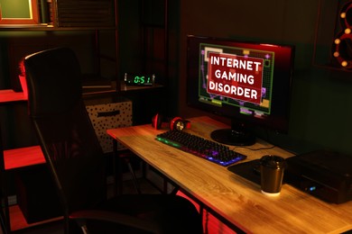 Image of Internet gaming disorder. Modern computer and RGB keyboard on wooden table in dark room