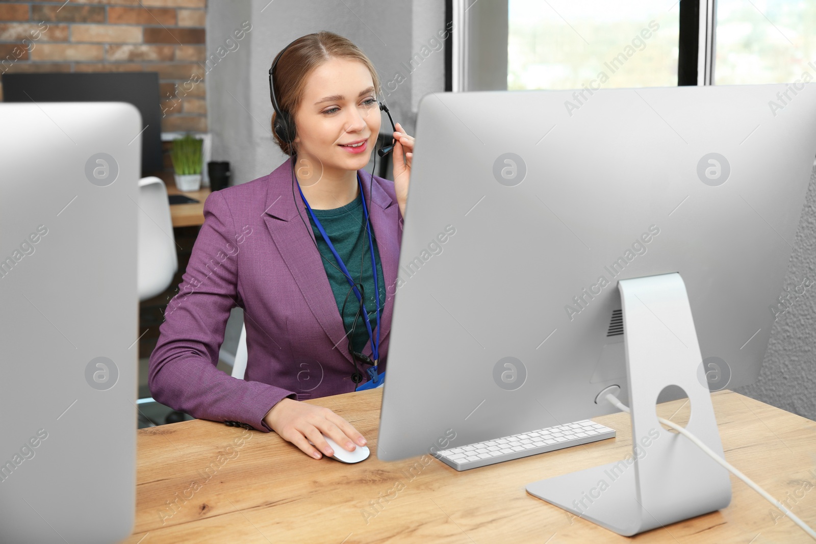 Photo of Technical support operator working with headset and computer at table in office