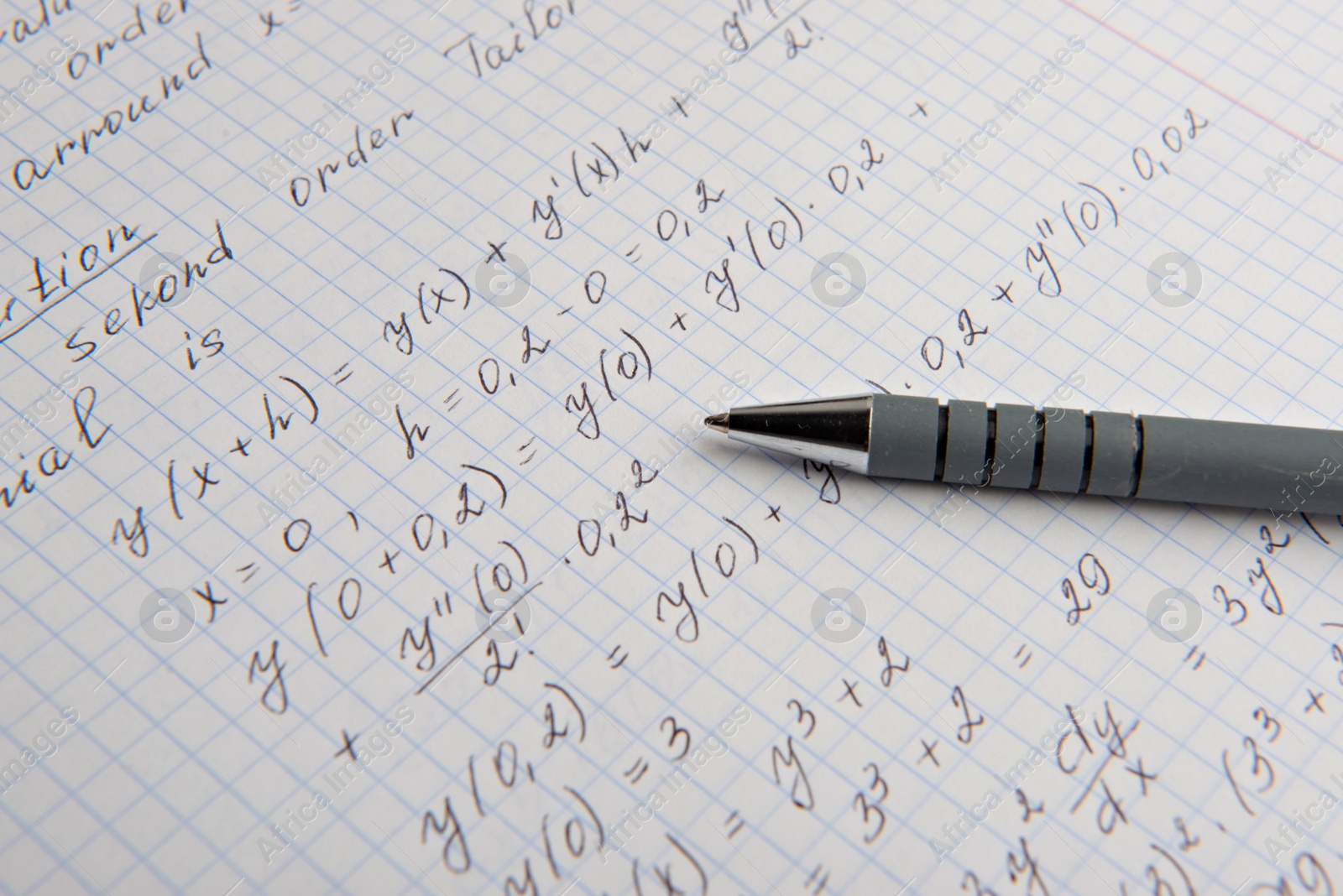 Photo of Paper with written mathematical calculations and pen, closeup