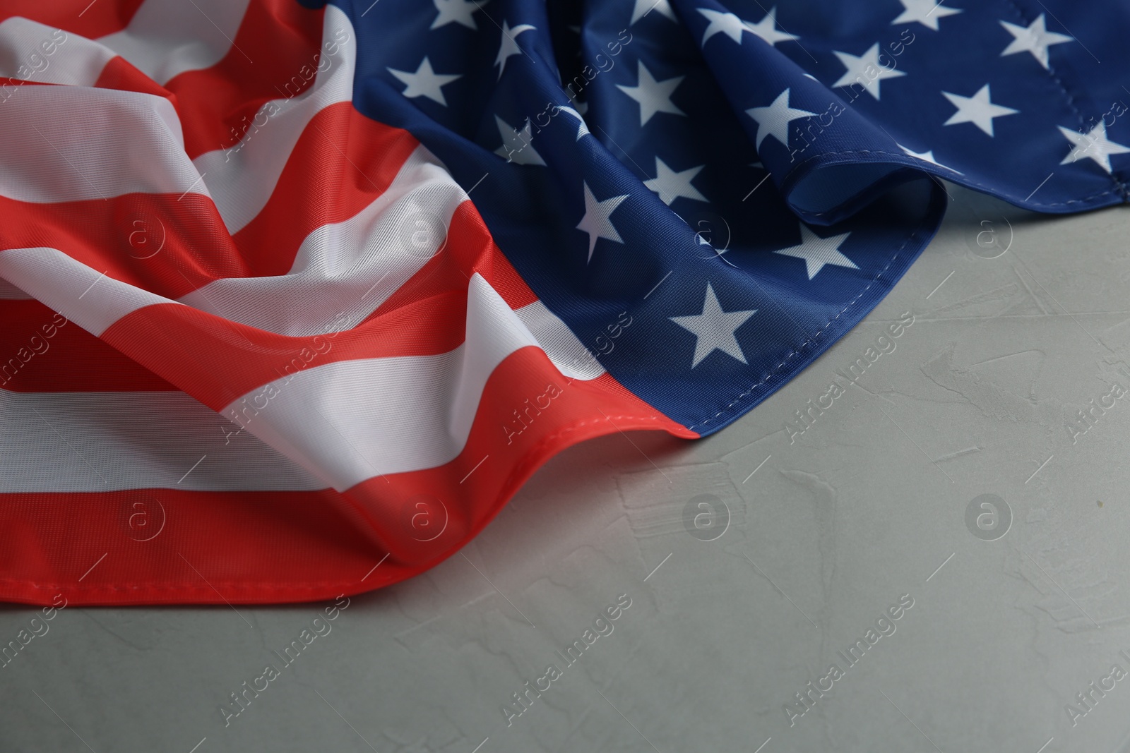 Photo of Flag of USA on light grey table, closeup. Space for text