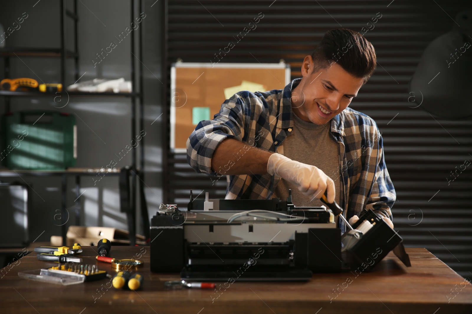 Photo of Repairman with screwdriver fixing modern printer in office