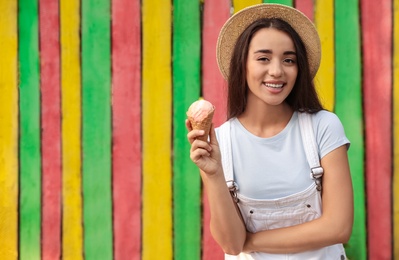 Photo of Happy young woman with delicious ice cream in waffle cone outdoors. Space for text