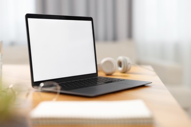 Laptop with blank screen on wooden table in room