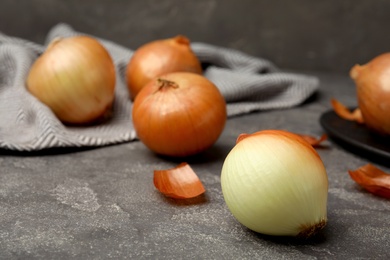 Ripe onions on grey table, space for text