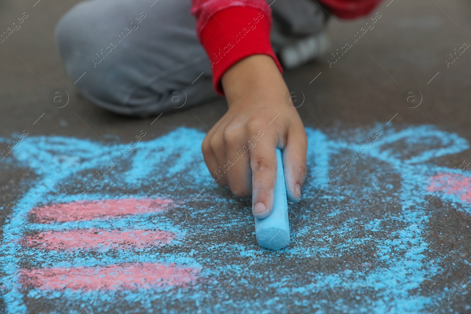 Photo of Child drawing cat with chalk on asphalt, closeup