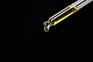 Photo of Dripping tincture from pipette on black background, closeup. Space for text