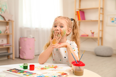 Cute little child painting with palms at table