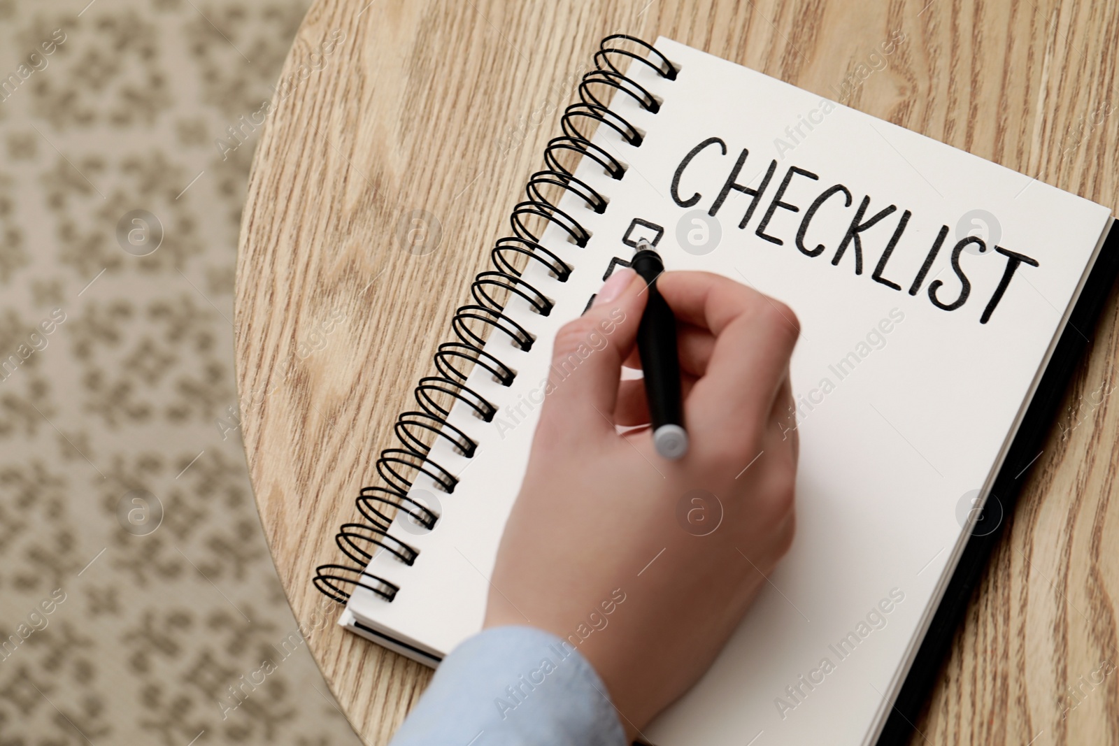 Photo of Woman filling Checklist with at wooden table, above view. Space for text