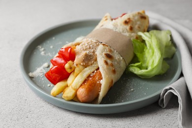 Delicious pita wrap with sausage, french fries and vegetables on light gray table, closeup