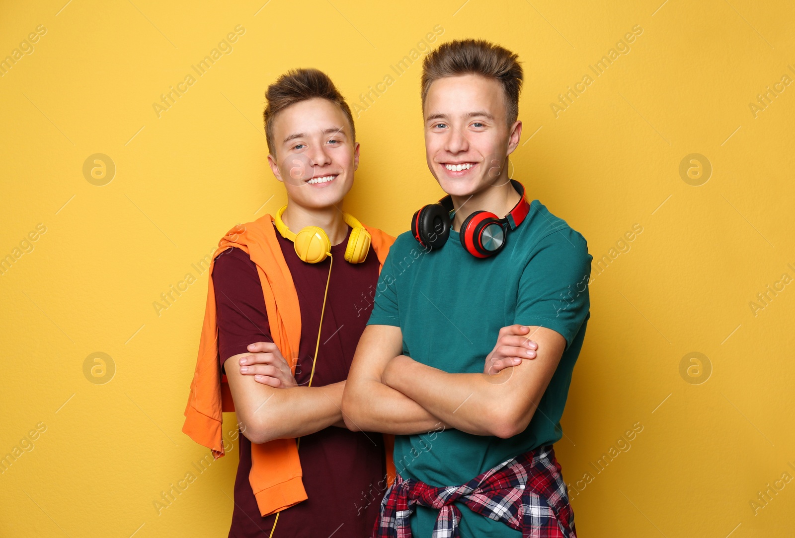 Photo of Teenage twin brothers with headphones on color background