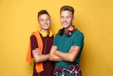 Photo of Teenage twin brothers with headphones on color background