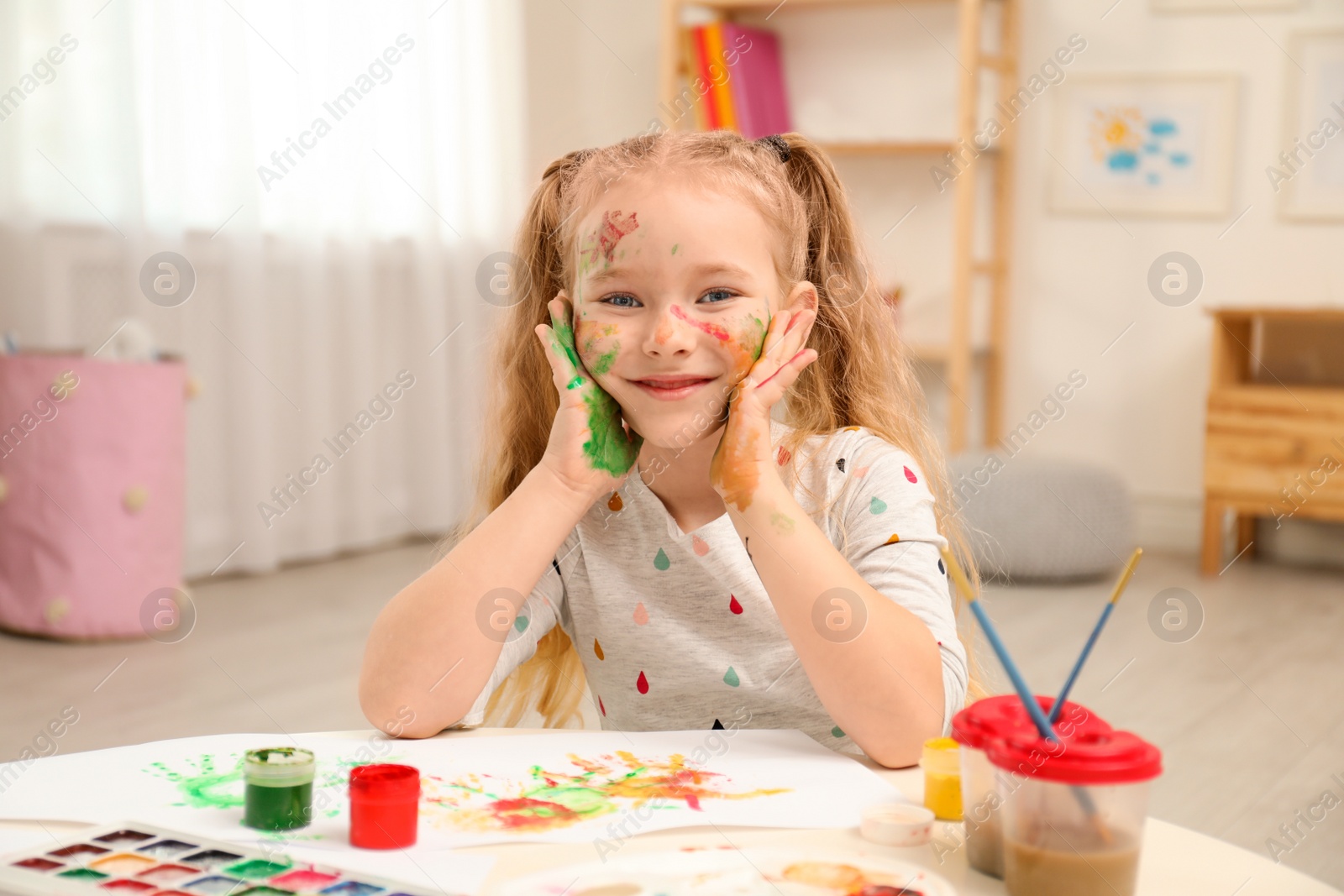 Photo of Cute little child painting with palms at table