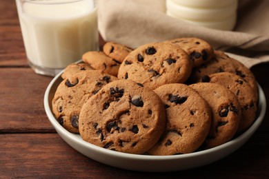 Delicious chocolate chip cookies and milk on wooden table, closeup