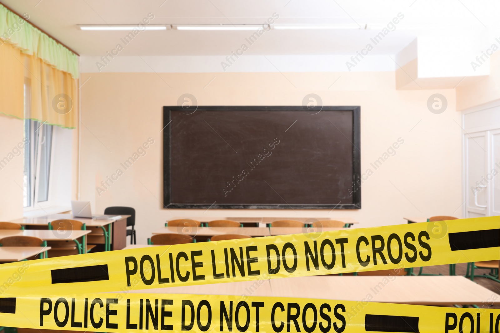 Image of Yellow crime scene tape in empty school classroom