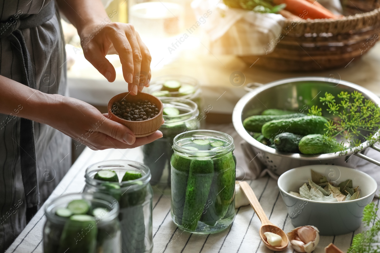 Photo of Woman putting spices into jar in kitchen, closeup. Canning vegetables