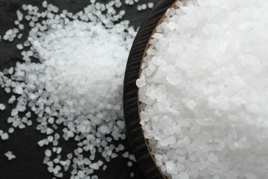 Photo of Plate with natural sea salt on black table, closeup. Space for text