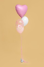 Photo of Bunch of heart and round shaped balloons for birthday party on beige background