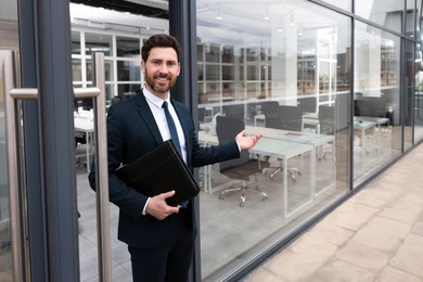 Photo of Male real estate agent with leather portfolio inviting inside