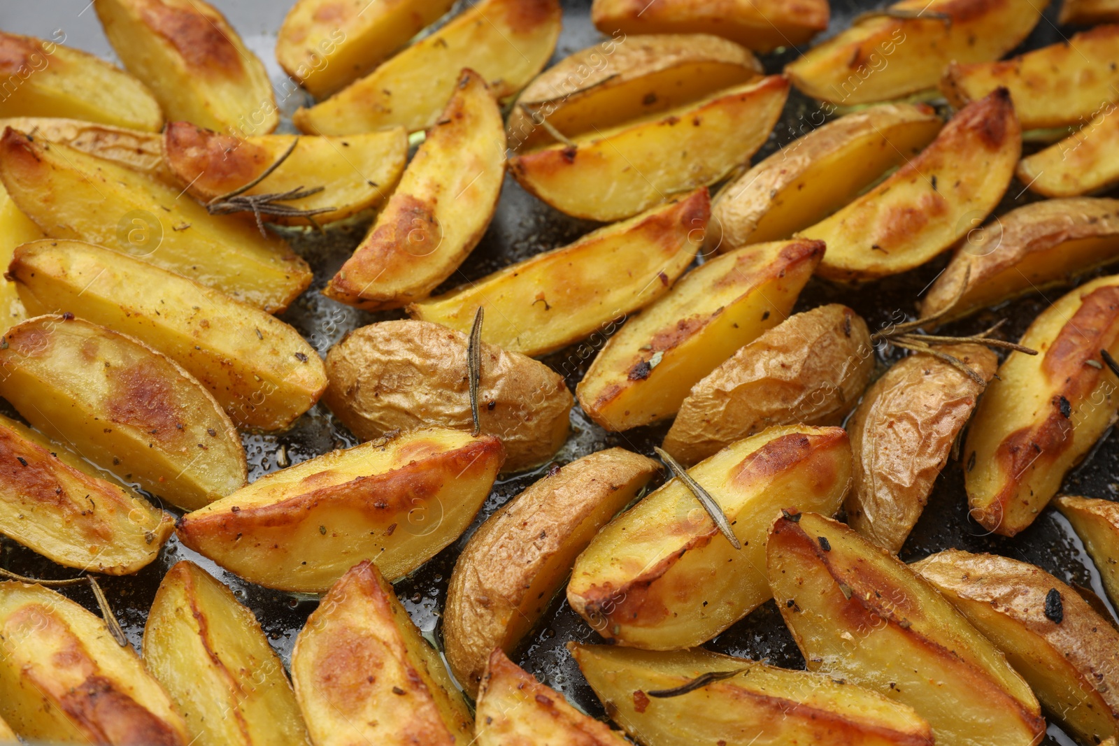 Photo of Delicious baked potatoes with rosemary on black surface, above view