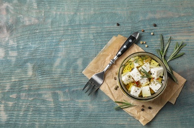 Flat lay composition with pickled feta cheese in jar on blue wooden table. Space for text